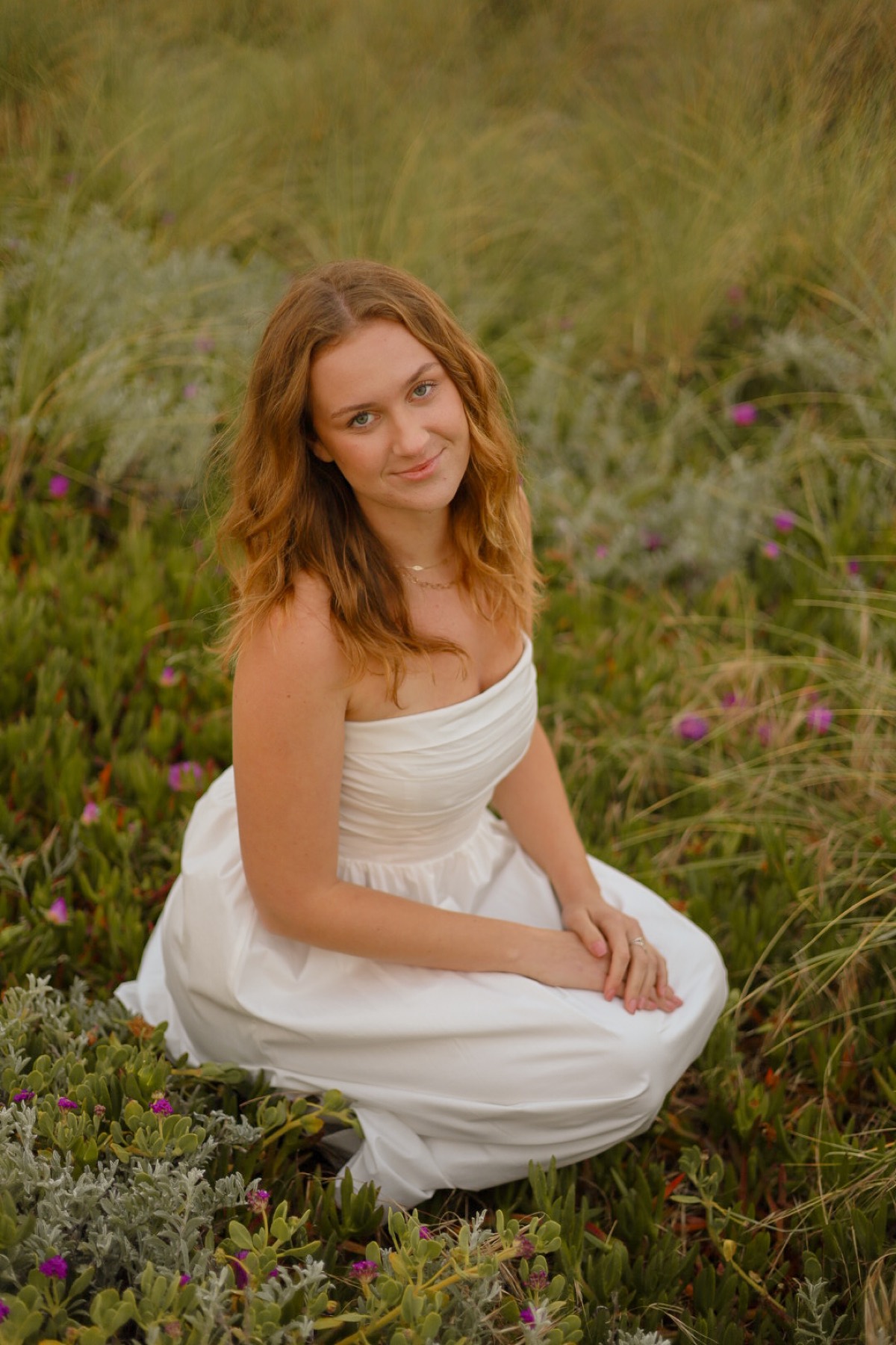 Portrait in a white dress kneeling in a green field