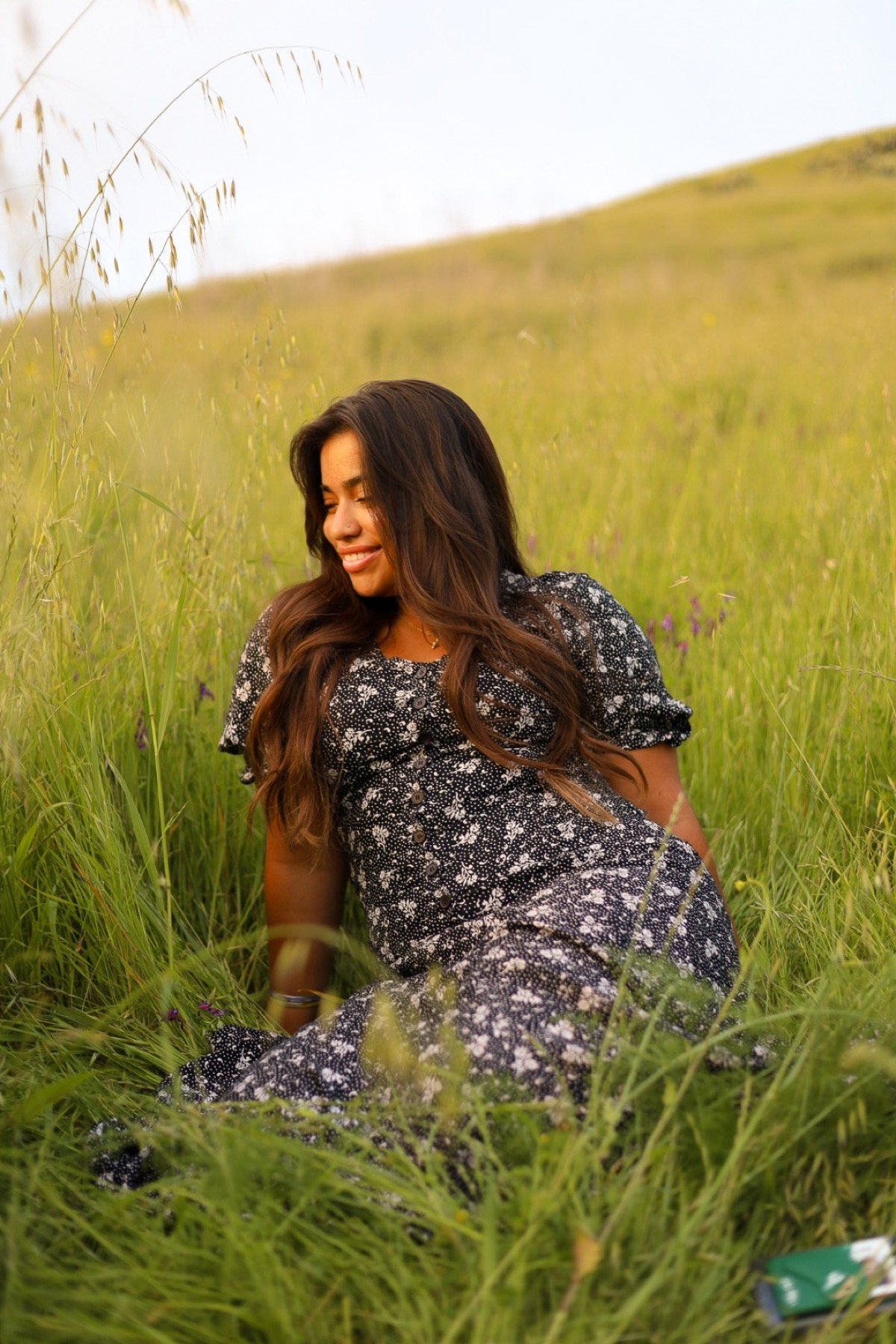 Portrait in a floral dress sitting in tall green grass